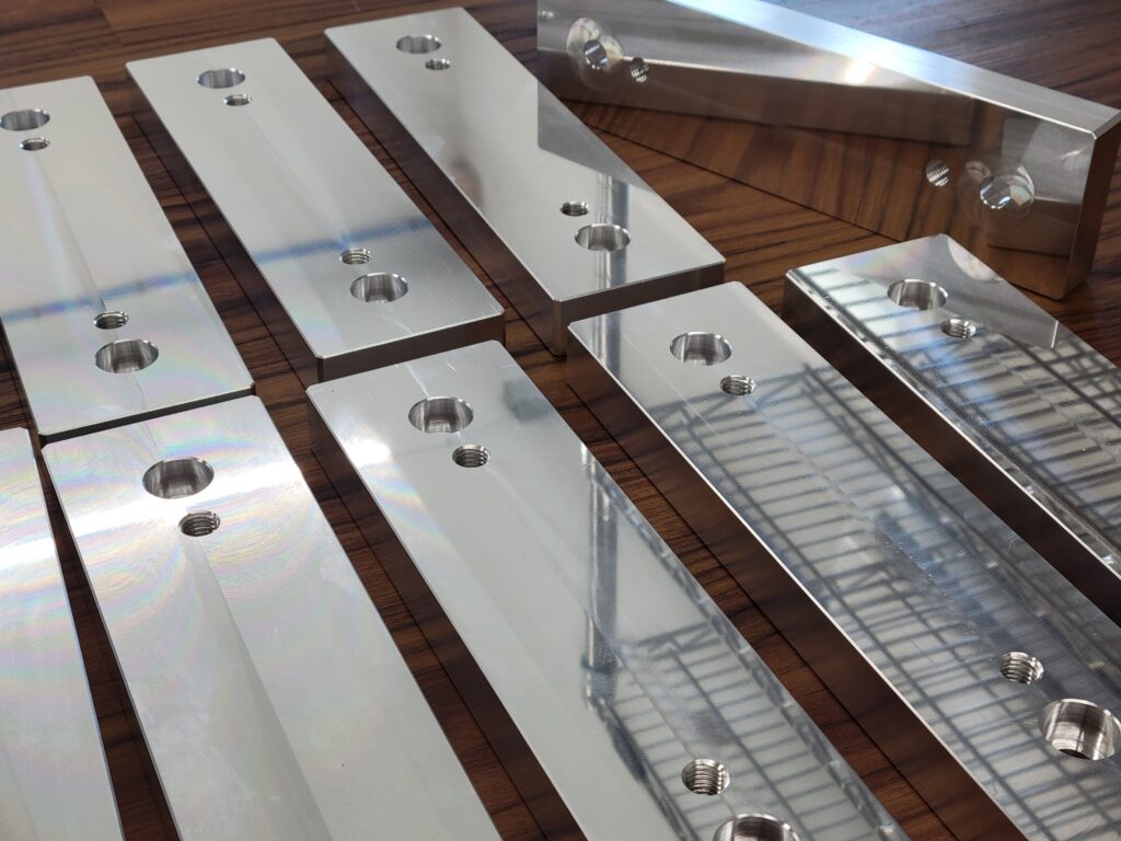 Aluminum manufactured parts with a bright reflective finish.